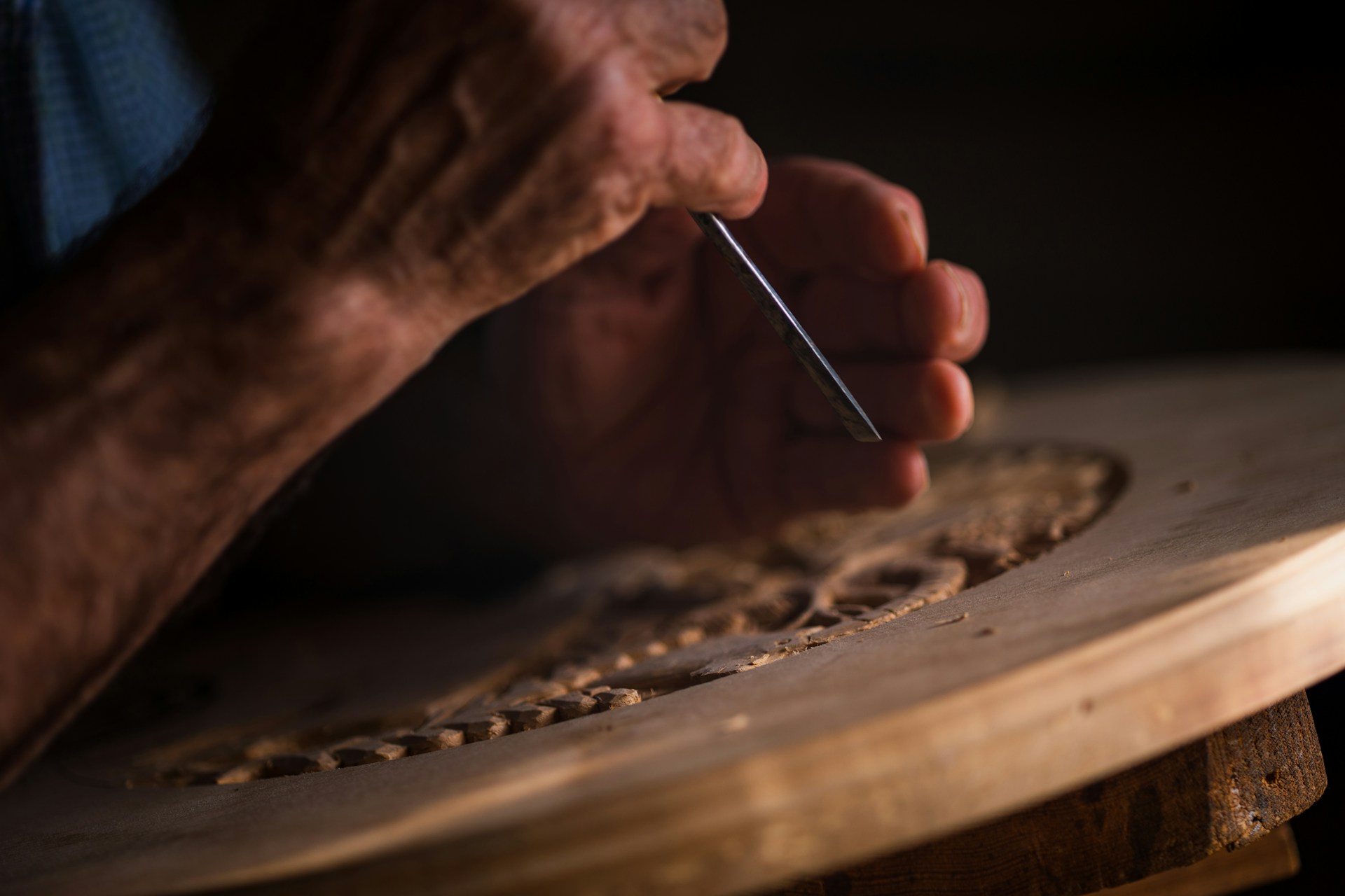 A craftsperson's hands cutting wood — the kind of close contact with the work that builds real skill
