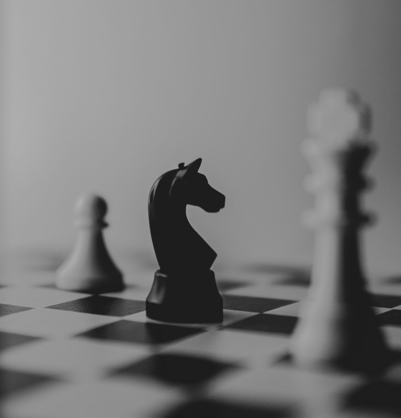 A black knight chess piece standing beside a rook on a chessboard
